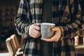 A man drinks tea or coffee in a modern cozy cafe. Cup in male hands close-up. Royalty Free Stock Photo