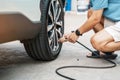 Man driver hand inflating tires of vehicle, removing tire valve nitrogen cap for checking air pressure and filling air on car Royalty Free Stock Photo