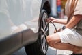 Man driver hand inflating tires of vehicle, removing tire valve nitrogen cap for checking air pressure and filling air on car Royalty Free Stock Photo