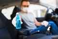 Man driver in protective mask with hands wearing rubber gloves holding alcohol sanitizer sprayer, covid-19 protection from