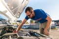 A man driver is repairing a truck with an open hood. Royalty Free Stock Photo