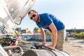 A man driver is repairing a truck with an open hood Royalty Free Stock Photo