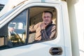 A man driver is sitting in the cab of a modern truck