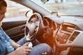 Man driver using mobile phone while sitting at the wheel of a car, sun glare Royalty Free Stock Photo