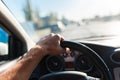 A man driving a car, focus on the left hand held on steering wheel Royalty Free Stock Photo