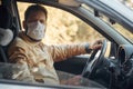 a man driving a car puts on a medical mask during an epidemic, a taxi driver in a mask, protection from the virus