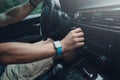 Man driving a car and tuning radio, smart watch on the hand, inside