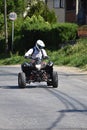 A man with driving equipment drives a quad along an asphalt road