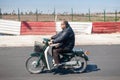 Man driving his black moped on the side of the road in Marrakesh, Morocco