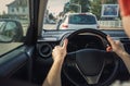 Man driving his car on the city street, close up of person hands on the steering wheel