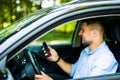 Young man driving in his car using cell mobile phone, dangerous situation Royalty Free Stock Photo