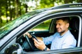 Young man driving in his car using cell mobile phone, dangerous situation Royalty Free Stock Photo