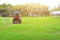 A man driving a lawn mower On a large football field, in the morning time, outdoors, gardening ideas