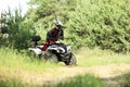 Man driving modern quad bike on sandy road near forest. Extreme sport Royalty Free Stock Photo