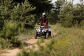 Man driving modern quad bike on sandy road near forest. Extreme sport Royalty Free Stock Photo