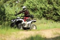 Man driving modern quad bike on sandy road near forest. Extreme sport Royalty Free Stock Photo