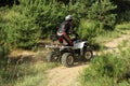 Man driving modern quad bike on sandy road near forest. Extreme sport Royalty Free Stock Photo