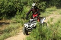 Man driving modern quad bike on sandy road near forest. Extreme sport Royalty Free Stock Photo