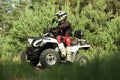 Man driving modern quad bike on sandy road near forest. Extreme sport Royalty Free Stock Photo