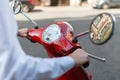 A man driving a red classic scooter rides on the asphalt in the city. Close - up of man's hands holding on to the red scooter's Royalty Free Stock Photo