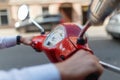 A man driving a red classic scooter rides on the asphalt in the city. Close - up of man's hands holding on to the red scooter's Royalty Free Stock Photo