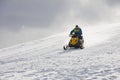 A man driving sports snowmobile in mountains.