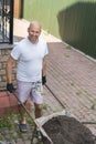 The man is driving a wheelbarrow with the ground. farmer with a wheelbarrow. A man in a white T-shirt carries land Royalty Free Stock Photo