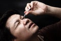 Man dropping eye drop medicine healing his eye pain with black background Royalty Free Stock Photo