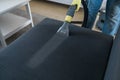 Man dry cleaner& x27;s employee hand in protective rubber glove cleaning sofa with professionally extraction method