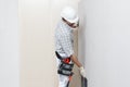 Man drywall worker installing plasterboard sheet to wall. Wearing hardhat, work gloves, safety glasses and tool belt. Isolated on