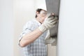 Man drywall worker or plasterer checking level of white plasterboard wall with bubble level at construction site. Wearing white Royalty Free Stock Photo