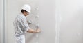 Man drywall worker or plasterer putting plaster on plasterboard wall using a trowel and a spatula, fill the screw holes, wearing