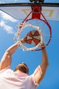 man dunking basketball ball through net ring with hands, sport success Royalty Free Stock Photo