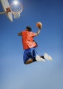 Man Dunking Basketball Into Hoop Against Blue Sky