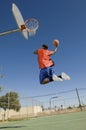 Man Dunking Basketball Into Hoop Against Blue Sky Royalty Free Stock Photo