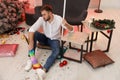 Man with dusting brush and mop suffering from hangover in room after New Year party Royalty Free Stock Photo