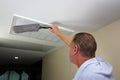 Man Dusting with a Dust Wand a Ceiling Furnace Air Intake Vent Grid