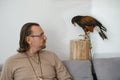 Man with eagle at home. Bird pet in hands