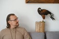 Man with eagle at home. Bird pet in hands