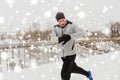 Man with earphones running along winter bridge