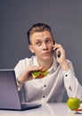 Man eat hamburger in office while call on his phone Royalty Free Stock Photo