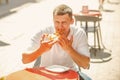 Man eat slice of pizza in street cafe. Happy macho enjoy snack on sunny outdoor, diet. Food and diet concept