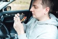 Man is eating black burger with meat, fish, tomato, salad, sause in car. Fast, safe, takeaway food on the road to coronavirus Royalty Free Stock Photo