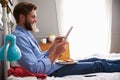 Man Eating Breakfast In Bed Whilst Using Digital Tablet Royalty Free Stock Photo