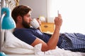 Man Eating Breakfast In Bed Whilst Using Mobile Phone Royalty Free Stock Photo