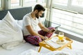 Man eating breakfast in bed whilst using mobile phone Royalty Free Stock Photo