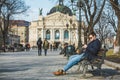 man eating burger surfing internet on phone sitting on bench