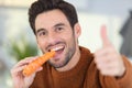 man eating carrot and holding thumb up Royalty Free Stock Photo