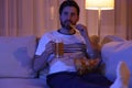 Man eating chips and drinking beer while watching TV on sofa at night. Bad habit Royalty Free Stock Photo