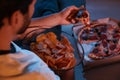 Man eating chips and pizza while watching TV on sofa at night, closeup. Bad habit Royalty Free Stock Photo